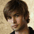 A single static image shows a person with brown hair in a black shirt against a light textured background.