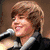 Four static views of a person with light brown hair in different outfits and backgrounds, including a microphone, white shirt, dark blue shirt, and light blue shirt.