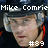 Pixelated image of a person with light skin and brown hair wearing a dark cap, with text reading "Mike Comrie" above and "#89" below.