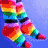 Rainbow-striped legs with red shoes on blue background, transitioning to a flower-like shape with multicolored petals and black center.