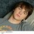 Pixelated close-up of a person with brown hair lying down, wearing a gray top against a dark background.