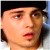 Pixelated close-up of a person's face with light skin tone, dark hair, and a dark headband, mouth slightly open, neutral expression.