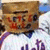 A pixelated figure in a white and purple sports jersey with a brown box on its head, showing slight variations in the box's position across frames.