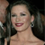A static image of a person with dark hair, red lipstick, and a light-colored strapless top against a dark background.