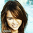 Pixelated portrait of a person with long brown hair against light blue background, static image.
