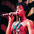 A pixelated image showing a person singing into a microphone on the left and green text reading "Original Icons .com" on the right against a dark background.