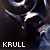 Pixelated image of a dark figure with a white star-like shape on chest, holding a long object, with 'KRULL' text at bottom.