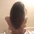 A pixelated image shows a person's back with dark hair, light skin tone, and visible ears against a soft beige background.