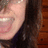 Pixelated close-up of a person's face with light skin tone, dark hair, and a dark garment against a brown background.