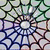 Stained glass pattern with repeating circular motifs and geometric shapes in blue, green, and brown tones.