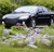 A pixelated image of a white car with dark accents on a grassy background, viewed from a low angle.