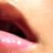 Close-up of lips with pink lower lip and dark red upper lip against light skin background.