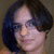 Two pixelated portrait images of a person with dark hair, one showing glasses and neutral expression, the other smiling without glasses.