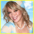 A pixelated image of a person with light brown wavy hair wearing a white pearl necklace and light blue top against a bright sky background.