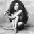 Black-and-white pixelated image of a person with long dark hair holding a white object, standing against a light background.