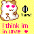 Pixelated cartoon cat with pink heart eyes, brown accents on ears and body, smiling mouth, standing against yellow background with 'Yum!' text and pink love declaration.