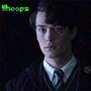 Two identical figures in dark robes and white collars stand side-by-side against a black background with green 'Whoops' text at top left.