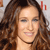 A static pixelated image of a person with long brown hair, closed eyes, and a smiling mouth, set against a light background with red elements.