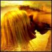 A blurry static image of two figures in close physical contact with warm yellow and orange tones dominating the scene.
