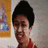 A pixelated static image shows a person with dark hair wearing a red top, standing in front of a wall with a framed picture.