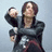 Pixelated image of a person in dark clothing holding an object, next to purple text on black background.
