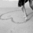 A person in dark clothing and white shoes draws a heart shape on the ground with their foot, then forms it with hands.
