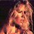 Pixelated close-up of a person with light brown hair against a dark background, showing partial facial features and clothing.
