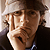 Pixelated static image of a person wearing a light-colored cap and dark clothing with visible facial features including eyes, nose, mouth, and ear.