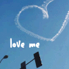 Blue sky background with white smoke forming a heart shape, traffic lights below, and 'love me' text in white pixelated font.