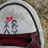 Pixelated icon shows two gray stick figures holding hands under a red heart, with dark curved lines above and maroon base against textured background.