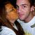 A pixelated image shows a person holding an orange object near their face, wearing a white shirt with dark sleeves.