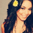 A pixelated image of a person with long dark hair, a yellow flower accessory, and a light-colored top against a neutral background.