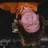 A pixelated image of a person with long hair and an orange head covering, next to an orange background with pixelated text.