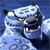 A pixelated blue-toned image of a stylized animal head with glowing yellow eyes and an open mouth showing teeth, set against a dark blue background.