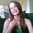 A pixelated static image shows a person with long brown hair wearing a dark green sleeveless top, seated against a blurred background.