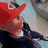 Animated sequence of a character in a red cap with a white 'G' logo, dark jacket, and light shirt, showing subtle facial expression changes against a blurred background.