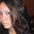 Pixelated close-up of a person with dark curly hair against a brown background, wearing a black top.