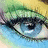 Pixelated close-up of a blue eye with green eyelashes and yellow hair, surrounded by pink text on black background.