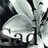 Pixelated grayscale icon with abstract shapes and dark edges, featuring a central light gray form against darker background elements.