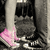 Pixelated static image shows a dark figure with pink accents against a gray background, featuring indistinct shapes and low-resolution details.
