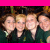 A bright pink background features two overlapping group photos of people in dark green uniforms with light collars, alongside pixelated text reading "HA HA HA. WE CUT OUT THE UGLY.".