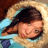 Pixelated image of a person with dark hair lying down, wearing light blue clothing against a beige background.