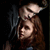 Pixelated image of a person with long brown hair wearing dark clothing against black background.