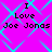 A static image with a bright pink background and cyan diamond-shaped patterns, displaying the text "I Love Joe Jonas" in black pixelated font across four identical sections.