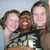 Three people pose closely together in a pixelated image with light blue background, wearing casual clothing.