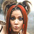 Static pixelated image of a person with red hair and dark accessories against a blurred background.