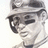 Pixelated grayscale image of a person wearing dark sunglasses and a light-colored cap, facing left with a neutral expression.