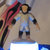 Pixelated figure with red hair and blue clothing stands against a light background with a bright blue and white base.