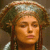Pixelated close-up of a person with light brown hair styled in braids, wearing a wide-brimmed hat with a light-colored band, against a muted brown background.