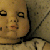 Pixelated image of a child's face with wide eyes and an open mouth, set against a textured background.